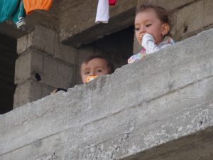 two Yazidi kids peeking over concrete